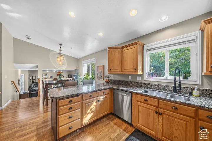 Kitchen featuring wood-finish flooring, granite countertops, wood cabinetry, and stainless steel dishwasher