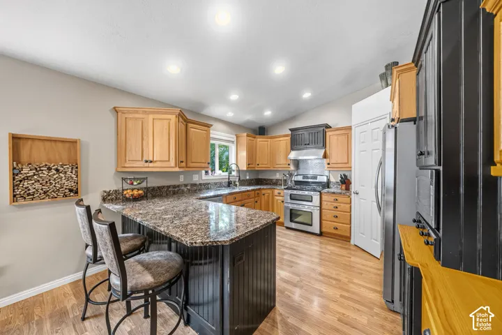 Kitchen featuring wood-finish flooring, recessed lighting, and a breakfast bar with beadboard paneling