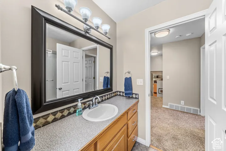 Vanity with an integrated sink, wood-finish cabinetry, and a textured countertop
