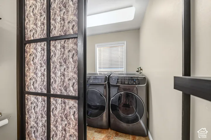 Laundry area with a window, textured flooring, and a flush-mount ceiling light