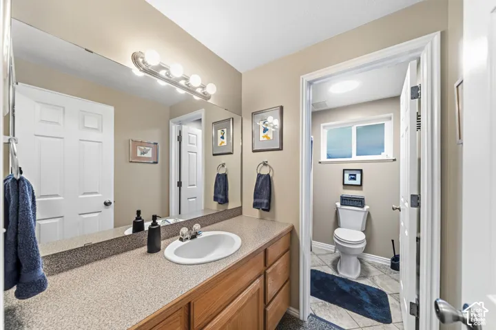 Bathroom vanity with an integrated sink, laminate countertop, wood-finish cabinetry, and a full-width wall mirror