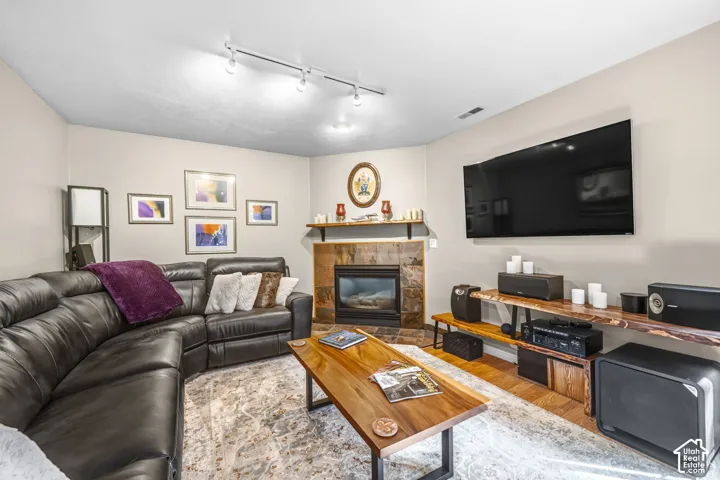 Corner fireplace with a stone surround, track lighting, and a wall-mounted display