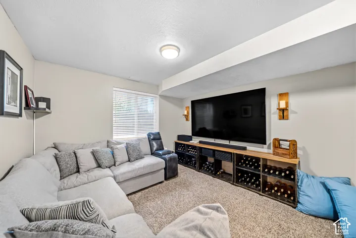 Recessed ceiling light, wall-mounted sconces, textured carpet, window with blinds, and built-in wine storage