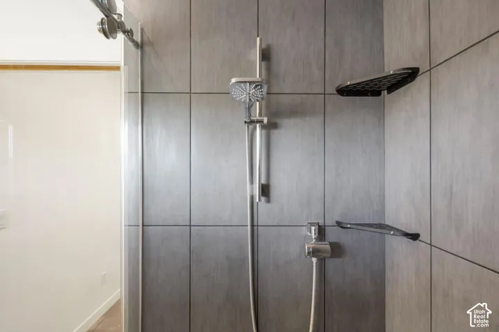 Shower with gray tile surround, rainfall showerhead, and handheld shower fixture