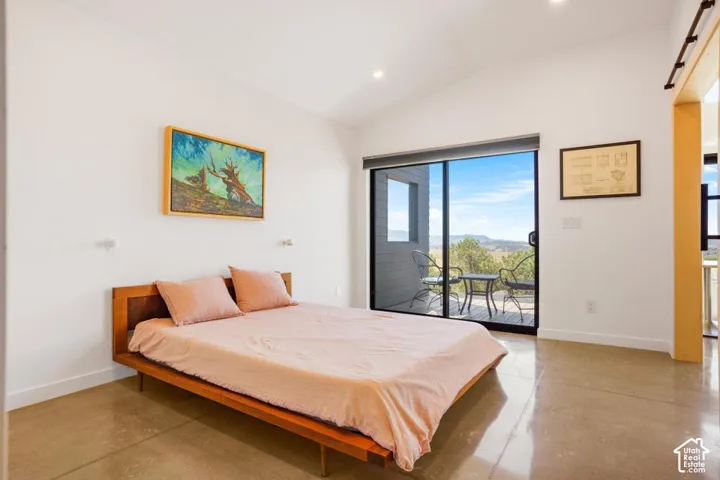 Polished concrete flooring, vaulted ceiling, recessed lighting, sliding glass door, and exterior decking