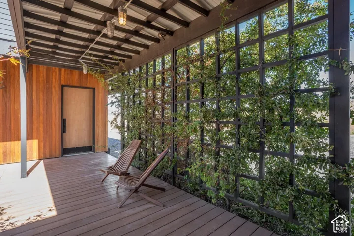 Covered porch featuring a wood-finish floor, wood-paneled exterior wall, and a slatted ceiling with exposed beams
