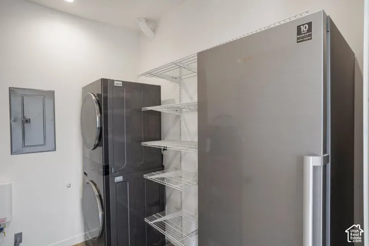 Dedicated utility area featuring a stacked washer and dryer, additional refrigeration, and wire shelving for storage