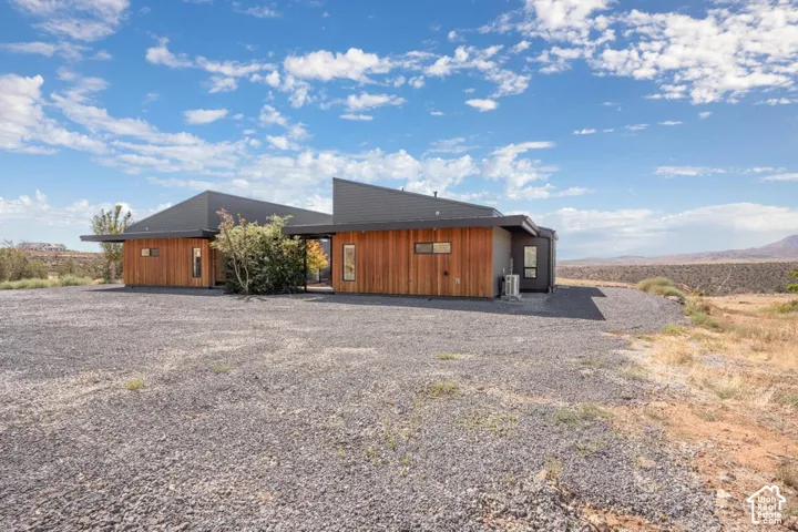 Modern architecture with wood paneling, dark roofline, and a gravel exterior