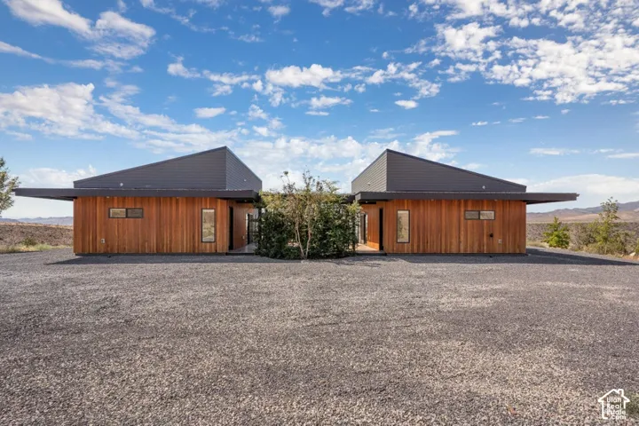 Modern architectural exterior featuring wood paneling, an angular metal roof, and large windows