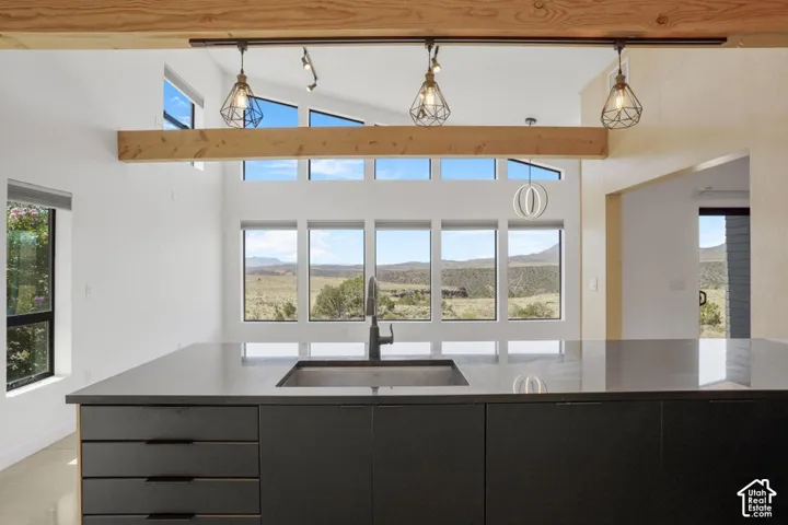 Kitchen island with a dark countertop, an integrated sink, and matte black cabinetry