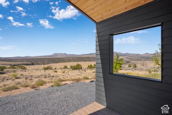 Dark gray horizontal siding with a horizontal window framing arid landscape, complemented by a wood-finish ceiling and flooring on the exterior
