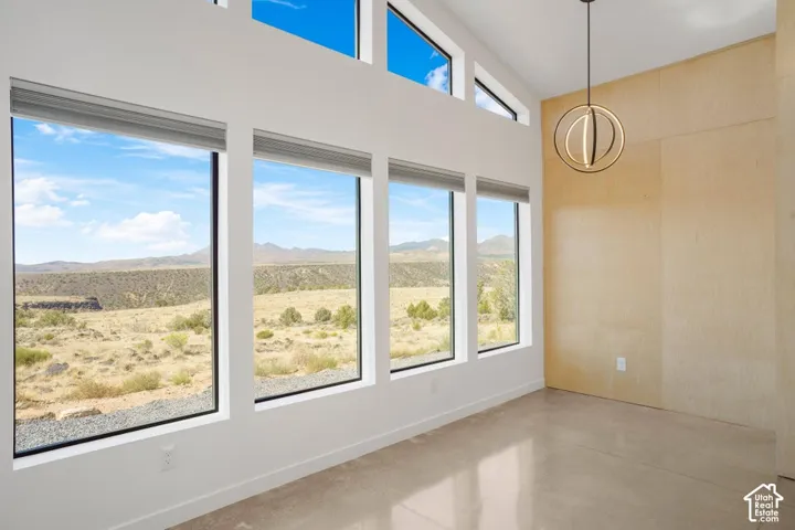 Expansive window wall with transom windows, polished concrete flooring, a decorative chandelier, and a wood-paneled accent wall