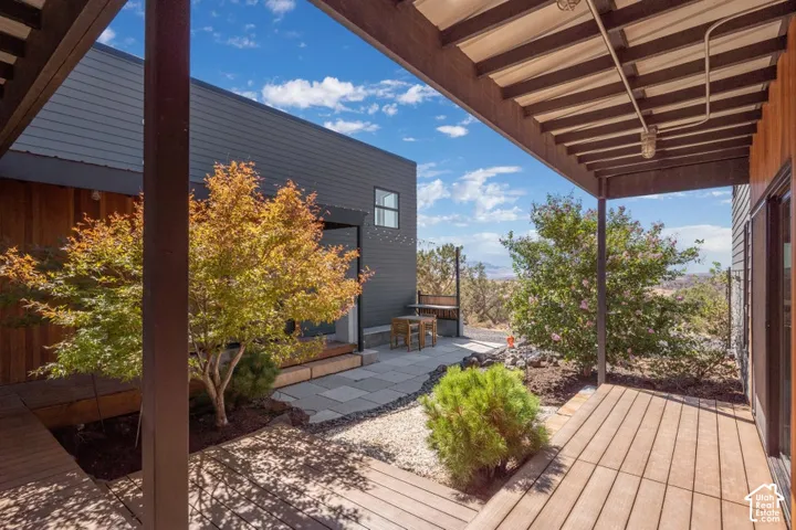 Outdoor living space featuring wood-finish decking, a covered patio, and a stone-paver courtyard