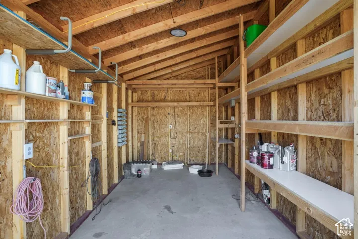 Concrete flooring, exposed wood beam construction, overhead lighting, integrated shelving, and wall-mounted storage hooks