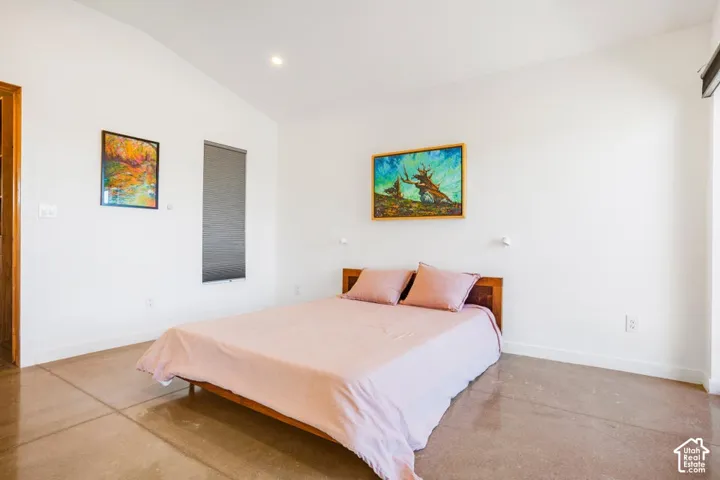 Vaulted ceiling, recessed lighting, polished concrete flooring, privacy window shade, wood-paneled doorway