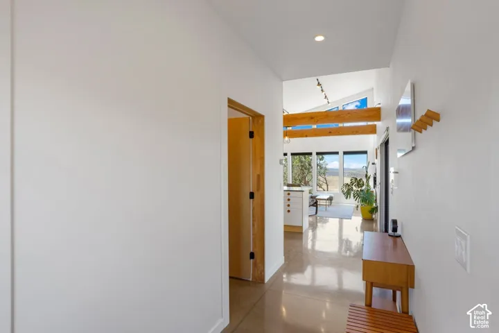 Polished concrete flooring, recessed lighting, exposed ceiling beams, and large picture windows