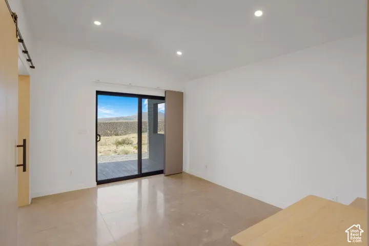 Sliding glass door to exterior patio, polished concrete flooring, recessed lighting, and a barn door entry