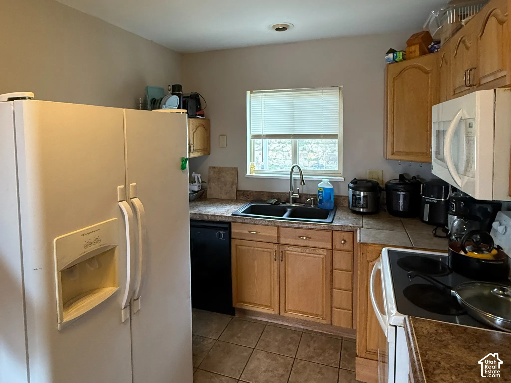 Kitchen featuring wood-finish cabinetry, tile flooring, and a double basin sink