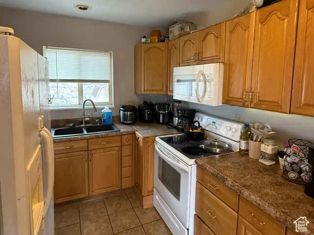 Ceramic tile flooring, laminate countertops, wood cabinetry, built-in microwave, and a double basin sink