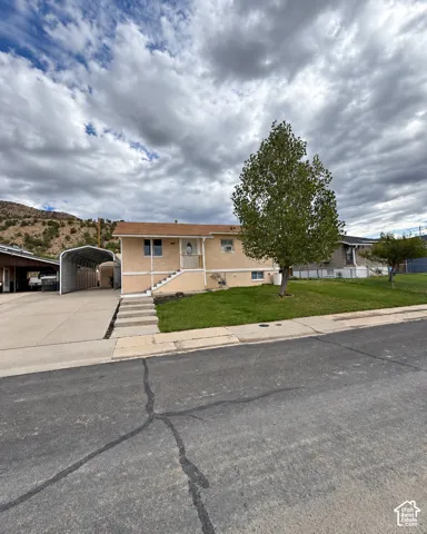 Exterior featuring a covered carport, concrete driveway, and front lawn
