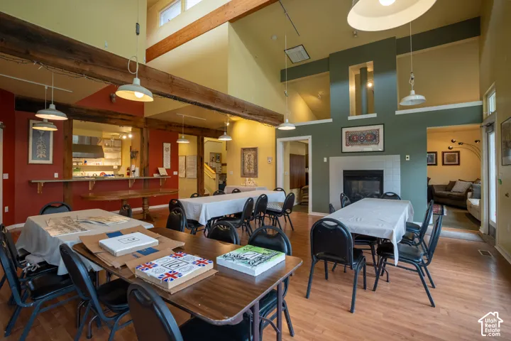 Spacious common area featuring wood-finish flooring, exposed wooden beams, a tiled fireplace, and a kitchen pass-through with a built-in counter