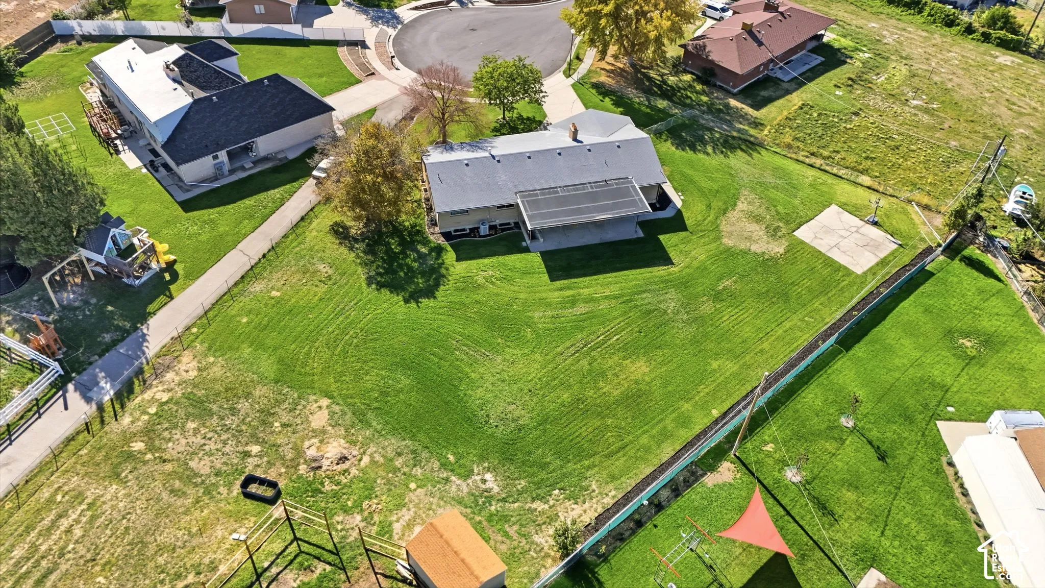 Expansive lot featuring a large grassy area, paved driveway, and detached shed structure