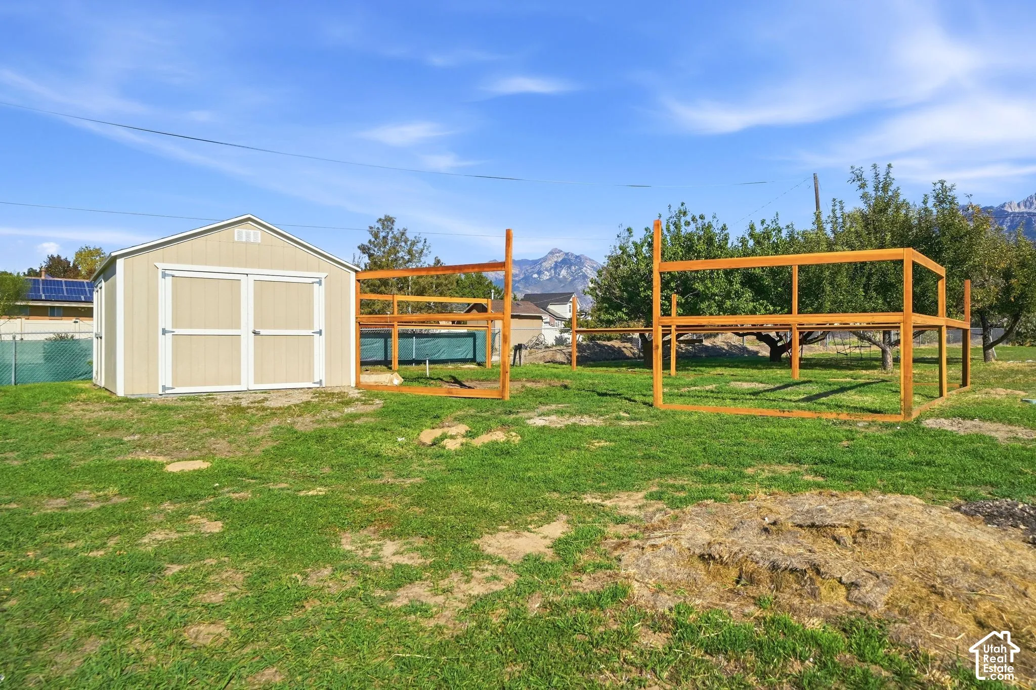 Expansive grassy area featuring a detached storage shed with double doors and a gable roof