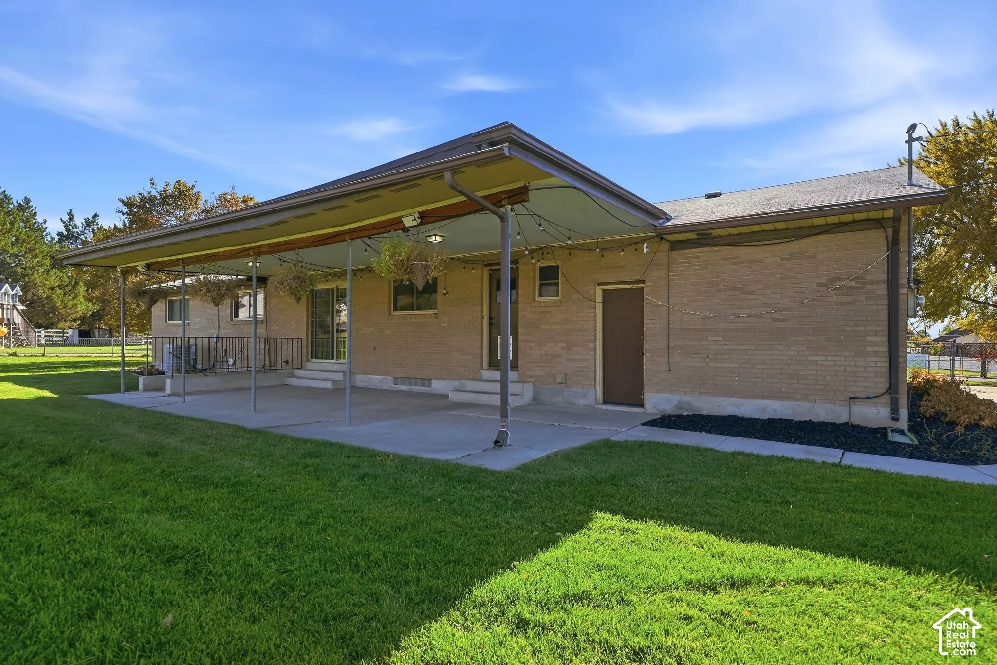Expansive covered patio with a concrete surface, supported by multiple columns, offering direct access to the interior via a sliding glass door
