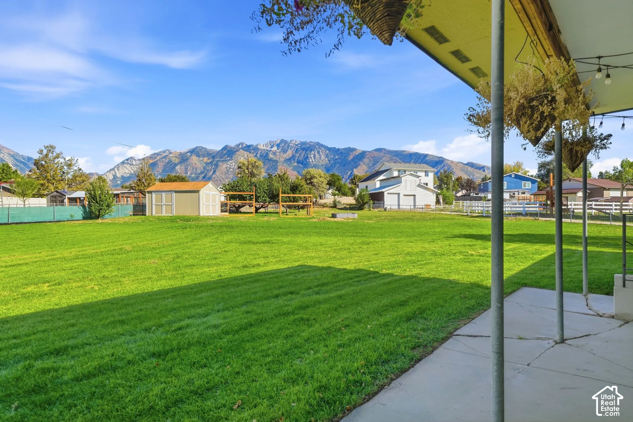 Expansive green lawn, mountain backdrop, covered patio, concrete patio surface, detached storage shed