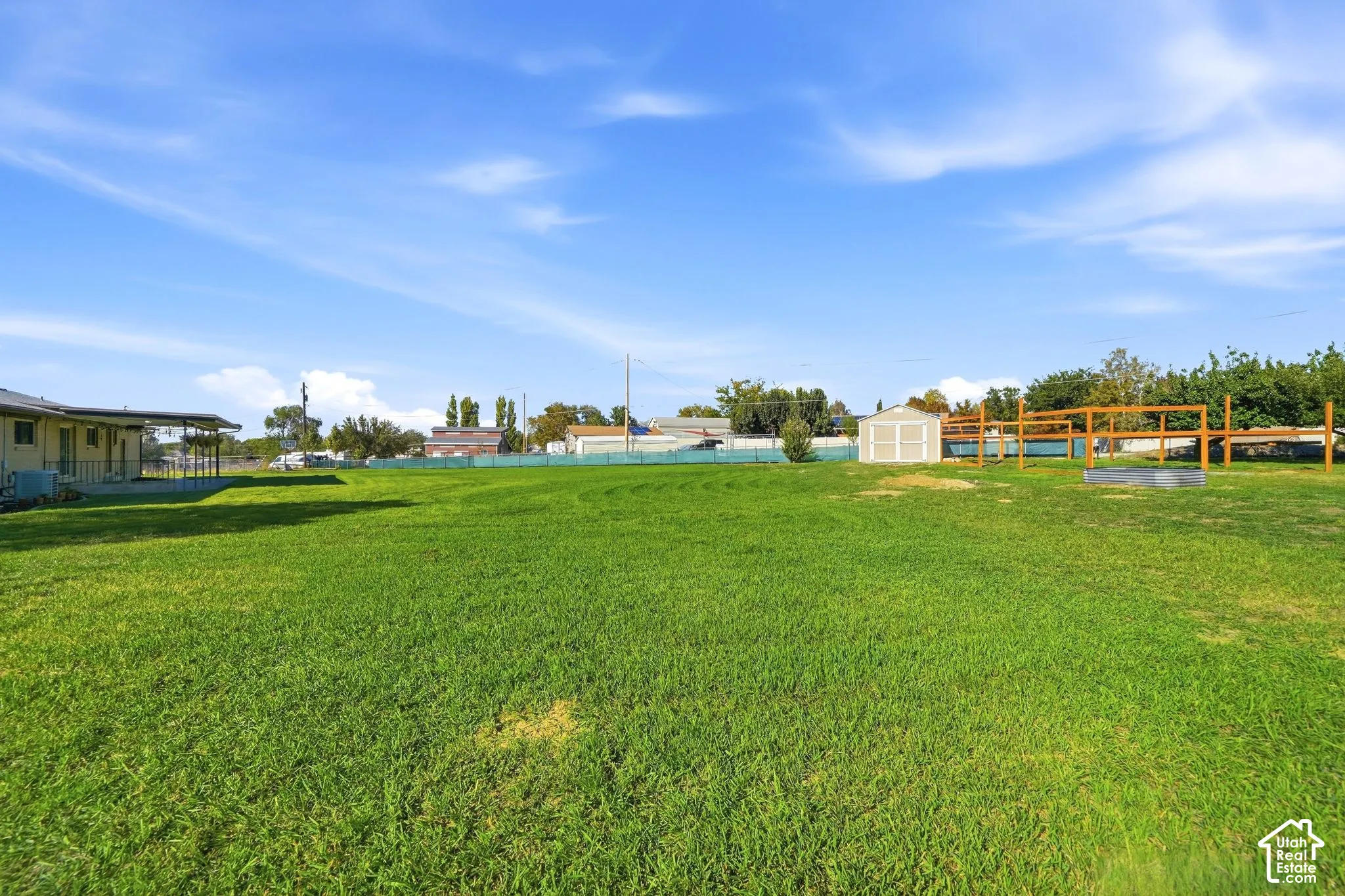 Expansive grassy area with a detached storage shed and a wood-framed structure