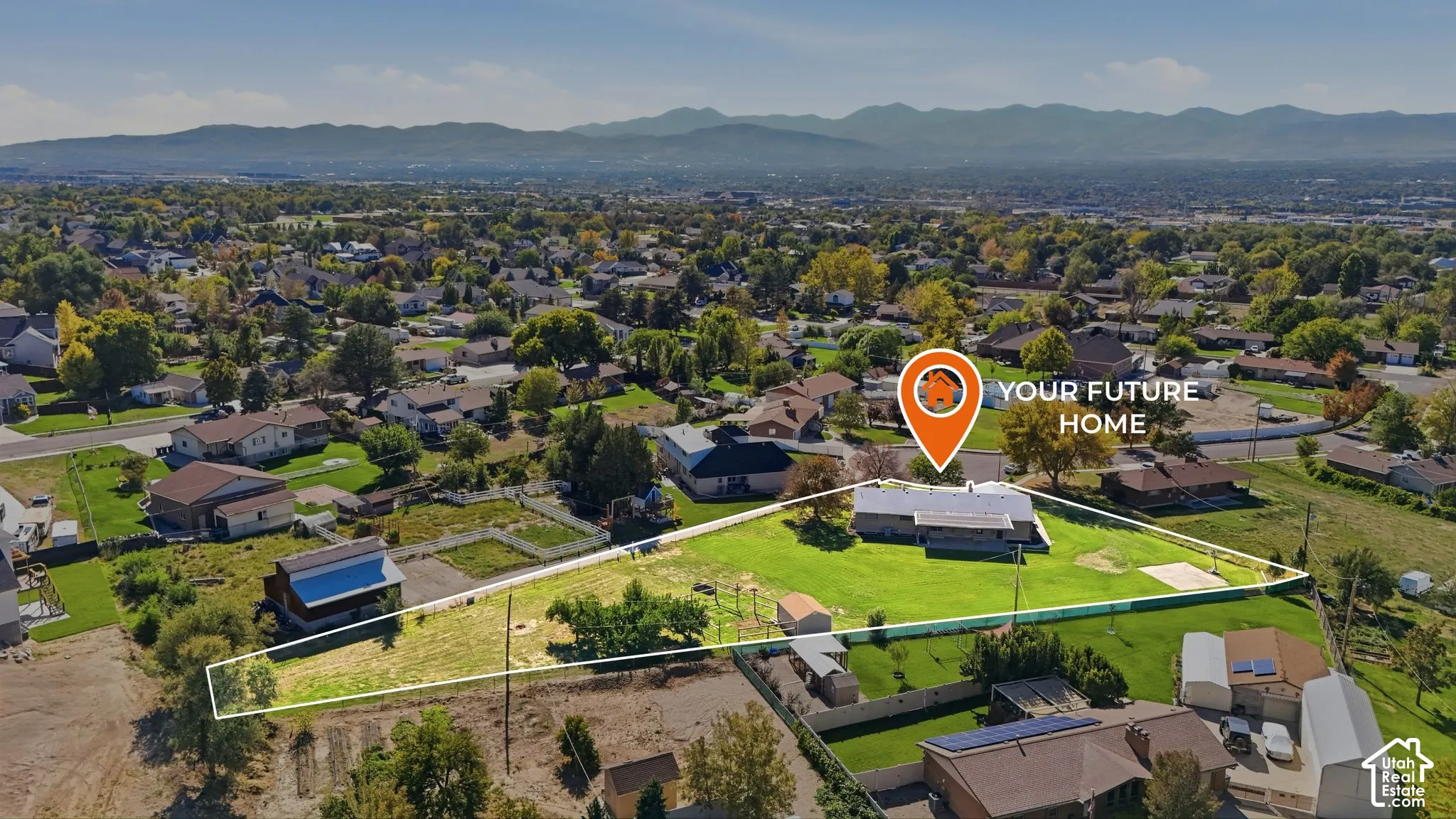 Expansive lot featuring a large lawn area, mature trees, and mountainous terrain in the background