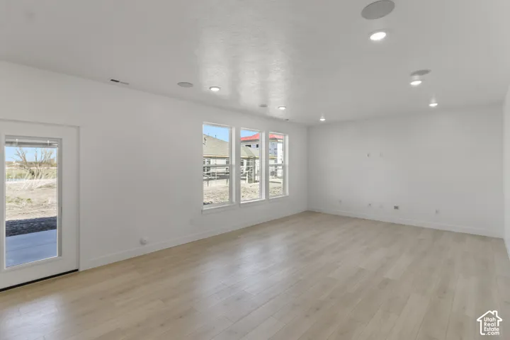 Recessed lighting, wood-finish flooring, white walls, multiple windows, and a glass-paneled door