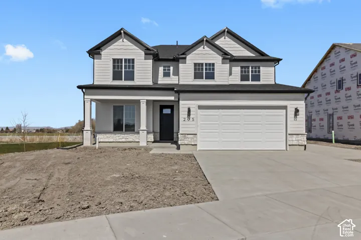 Contemporary two-story residence with white siding and dark trim, featuring a covered front porch with columns, an attached two-car garage, and a concrete driveway