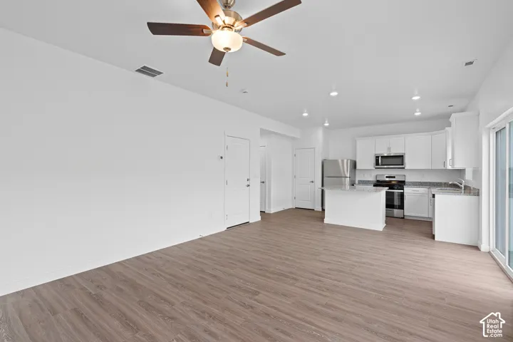 Open-concept living area with wood-finish flooring, recessed lighting, and a ceiling fan