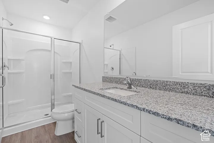 Walk-in shower with clear glass enclosure, white vanity with shaker-style cabinetry, chrome fixtures, and a speckled countertop
