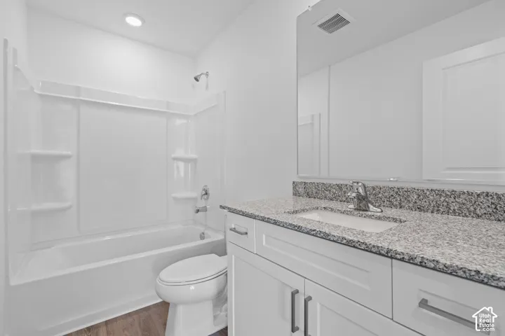Modern bathroom featuring a granite-topped double vanity with chrome hardware, white cabinetry, and a large illuminated mirror