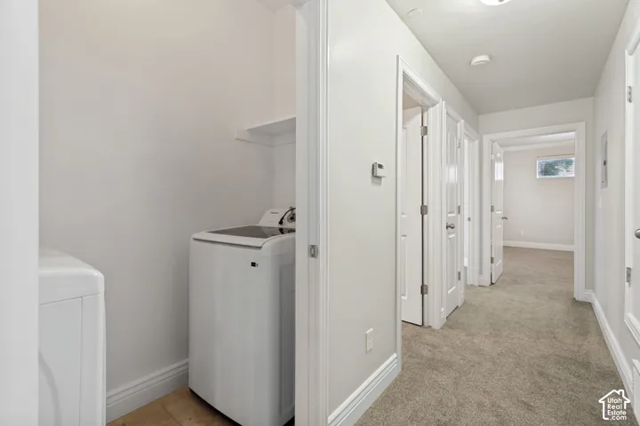 Laundry area with a built-in shelf and wood-finish flooring