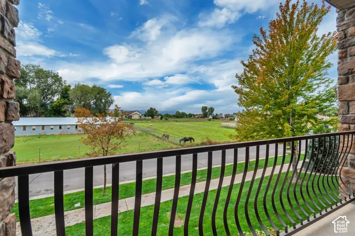 Stone pillar balcony with wrought iron railing overlooking expansive green fields