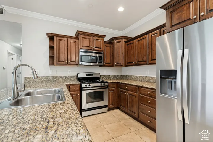 Kitchen featuring wood cabinetry, light-toned countertops, stainless steel appliances, and tile flooring