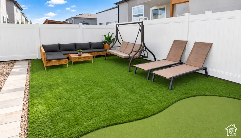 Fenced yard featuring a putting green, artificial turf, and a paver pathway