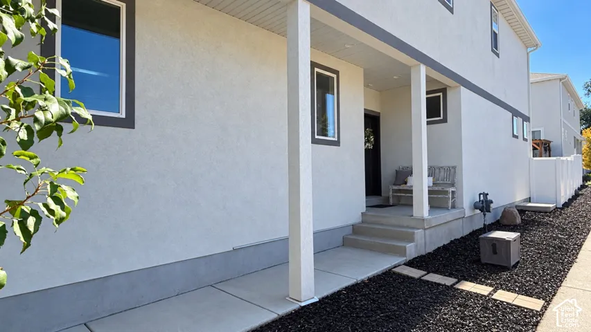 Stucco exterior with contrasting trim, covered entry porch, concrete steps, and a decorative rock landscaping bed with stepping stones
