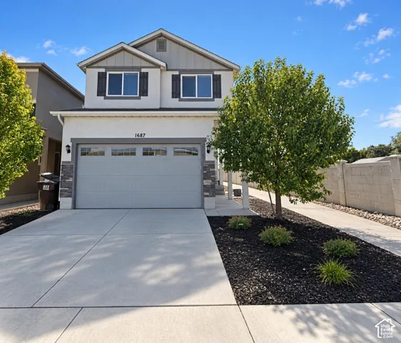 Two-story residence featuring a concrete driveway, attached two-car garage, and stone accents on the facade