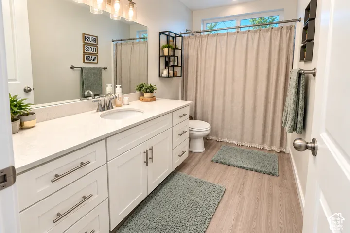 White vanity with brushed nickel hardware, light-toned wood-finish flooring, white countertop, and built-in shelving