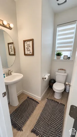 Pedestal sink with chrome-finish faucet, circular mirror, and wall-mounted vanity light