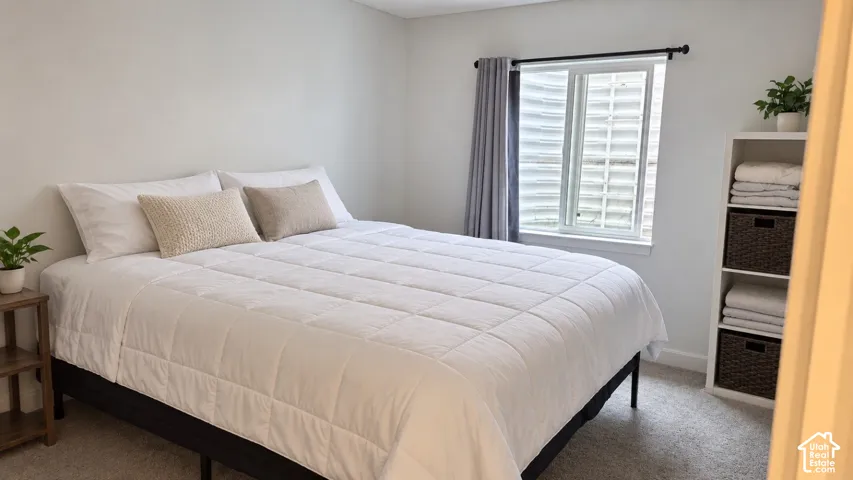 Carpeted room with a window featuring white blinds and gray curtains