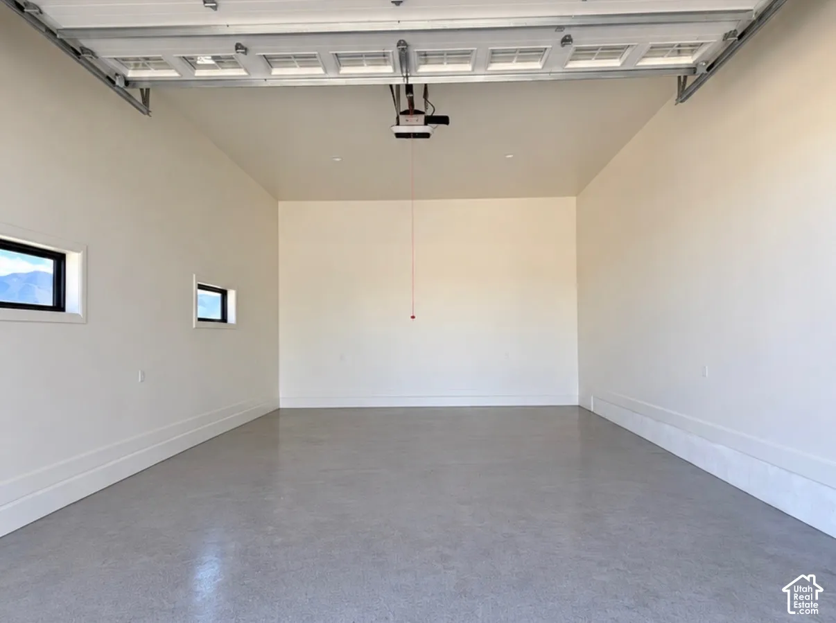 Polished concrete flooring, two rectangular windows, white painted walls, and a garage door opener