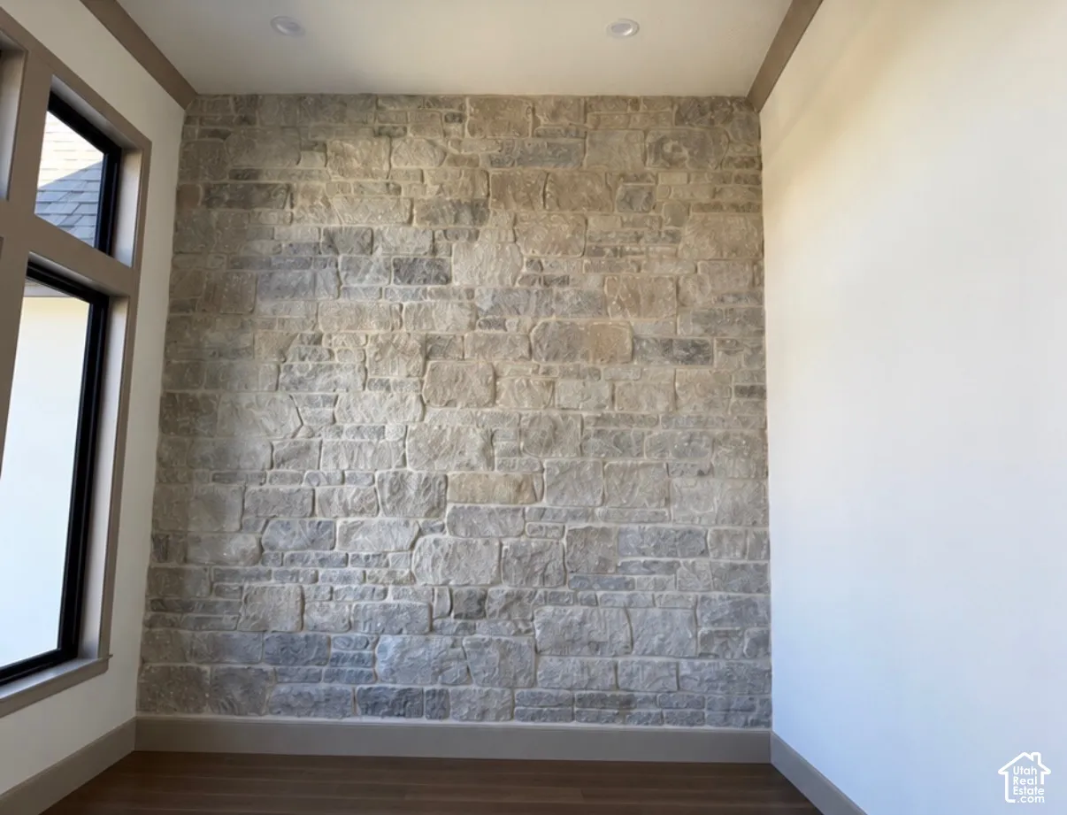 Stone accent wall with recessed lighting, wood-finish flooring, and a large window