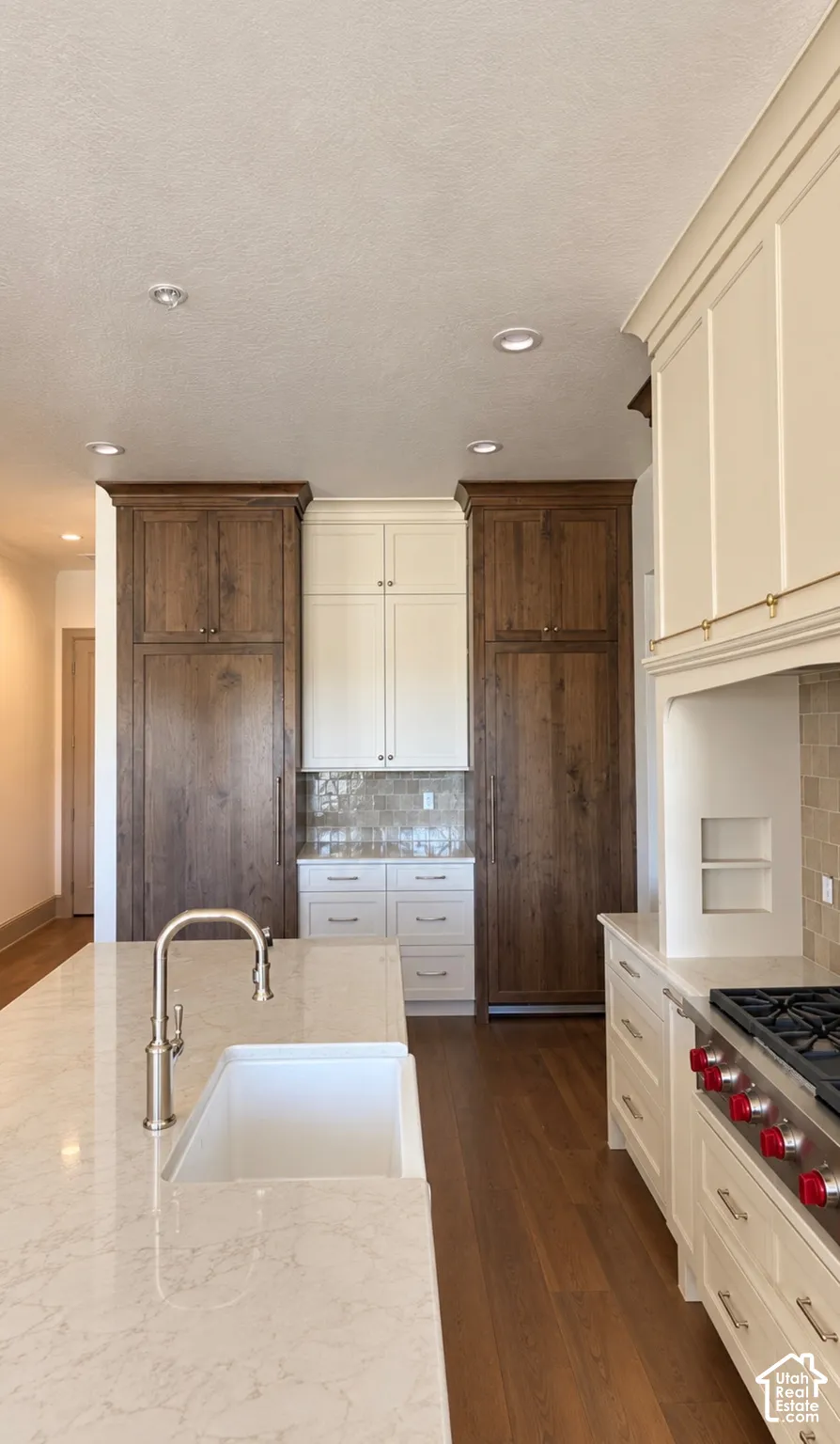 Kitchen featuring a large center island with an undermount sink, wood-finish flooring, recessed lighting, and a professional-grade range