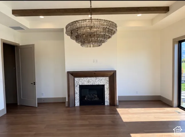 Wood-finish flooring, recessed lighting, and a tray ceiling with a dark wood beam