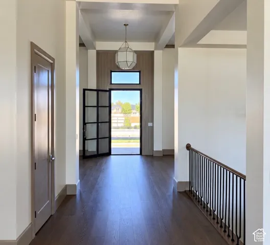 Front entry featuring a contemporary iron-framed glass door, wood-finish flooring, a coffered ceiling, and a decorative pendant light